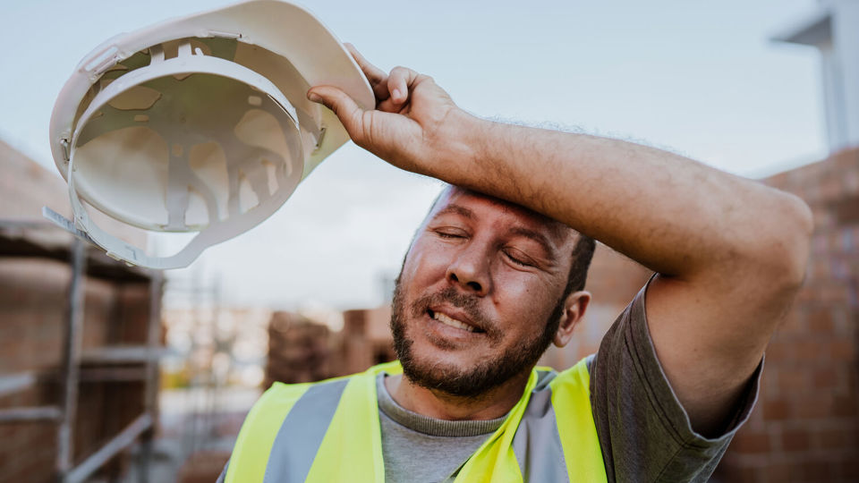 Construction worker removes hardhat in sun
