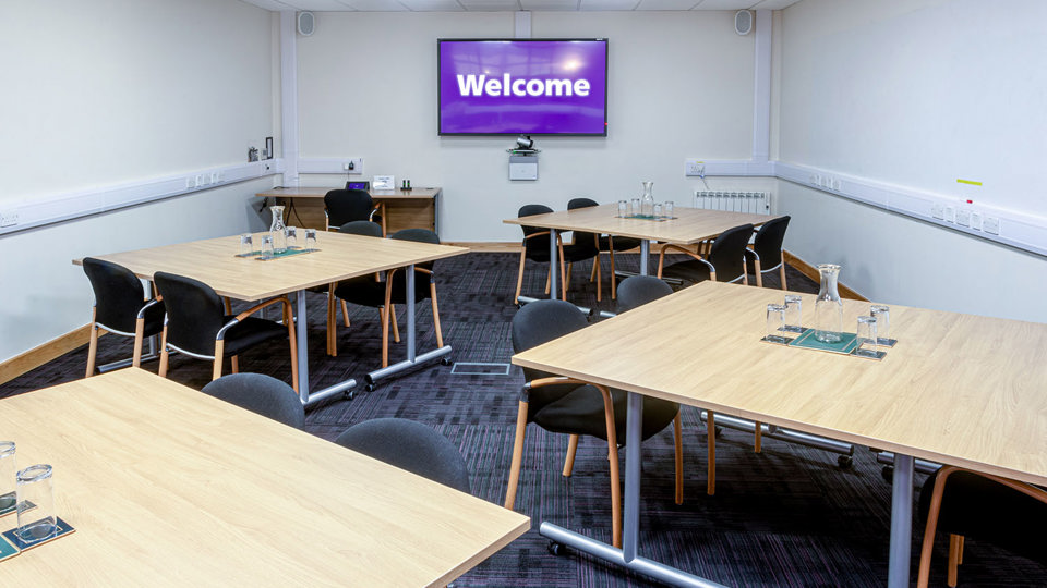 Groups of desks with four chairs at each in meeting room