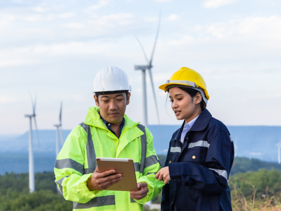 Two people looking at clipboard on a wind farm