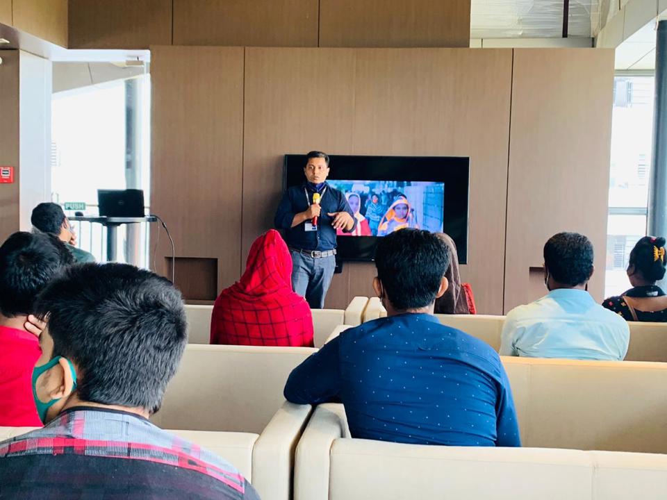Group attending an indoor presentation with a speaker at the front.