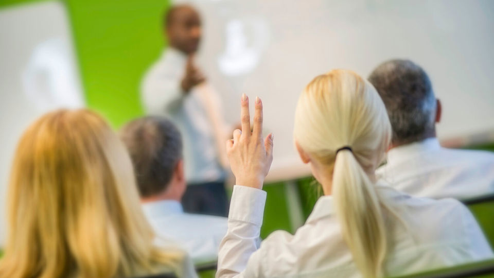 Woman in classroom raising hand