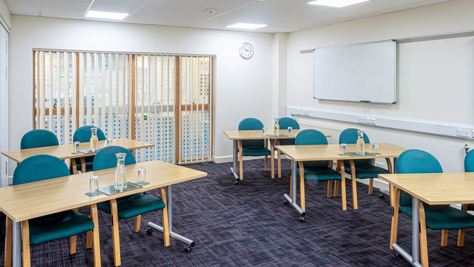 Meeting room laid out like a classroom, two chairs behind each desk