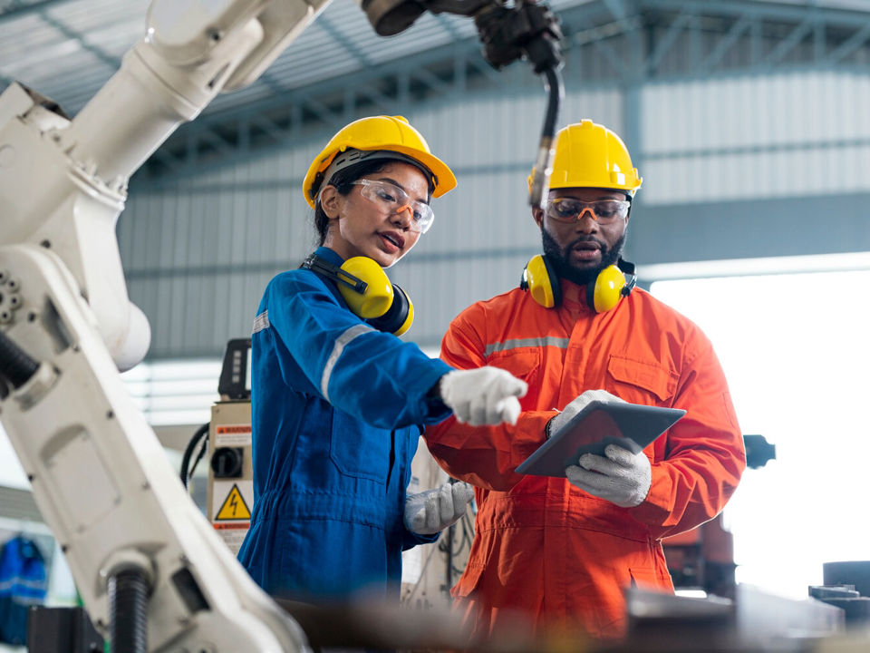 Woman and man working with a robot arm
