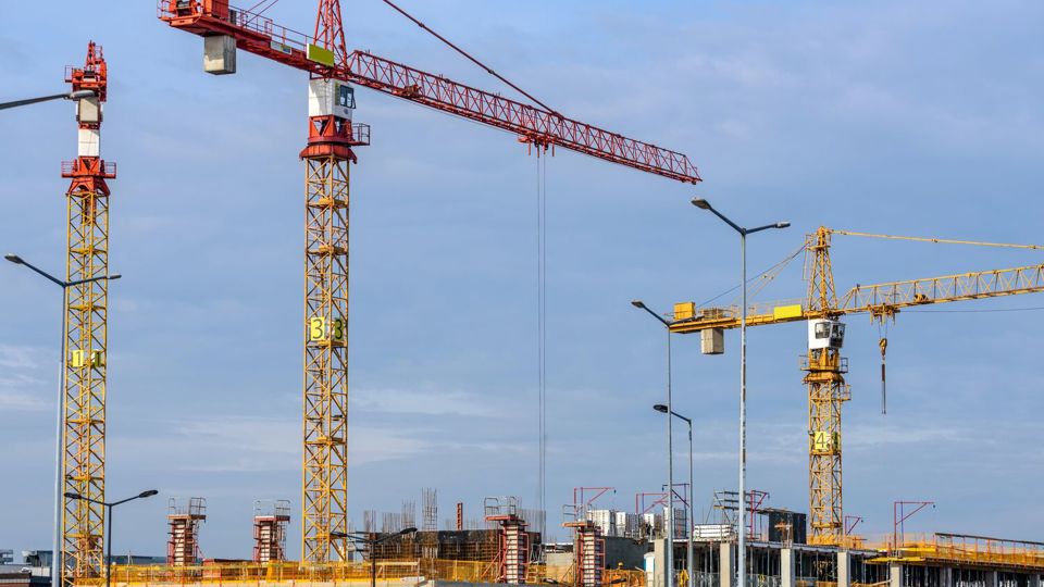 Three towering cranes on building site