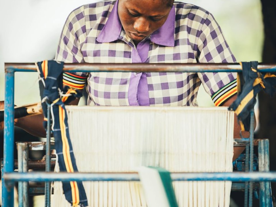 A textile weaver producing cloth on a manual hand machine in Ghana