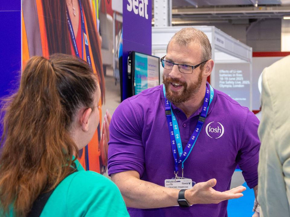 IOSH staff member offering help to visitor at event stand