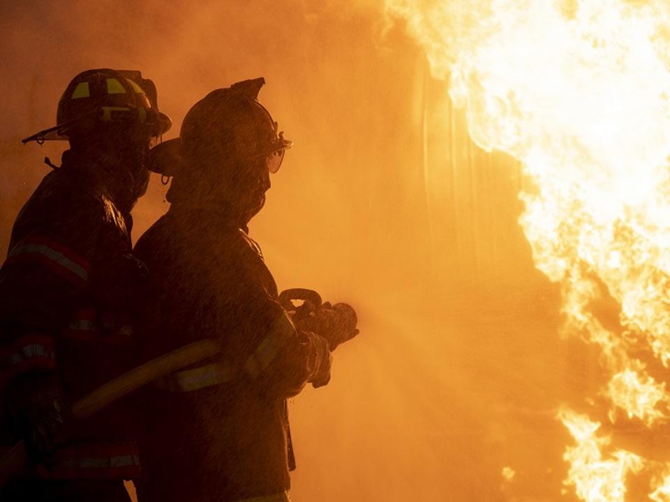 Two firefighters hosing down a fire