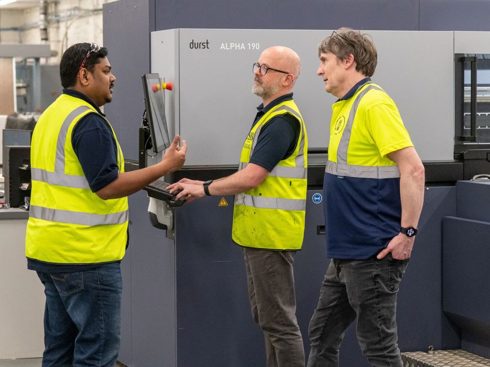 Three workers in high-vis jackets on factory floor